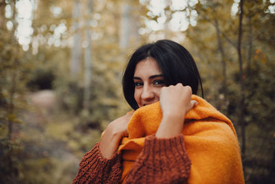 Portrait of young woman standing in forest during autumn