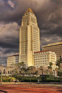 Buildings in city against cloudy sky