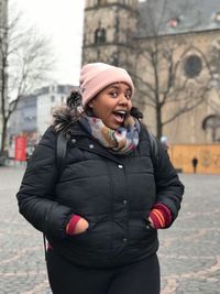 Young woman wearing hat standing in city during winter