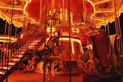 Illuminated carousel in amusement park at night