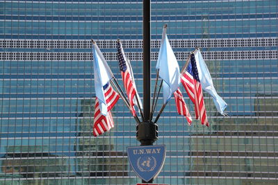 Low angle view of american flags and united nations flags against modern building