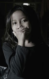 Close-up portrait of girl covering mouth at home