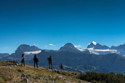 People on mountain against clear blue sky