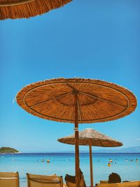 Low angle view of thatched roof against clear blue sky