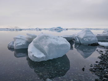 Frozen ice formations in lake against sky