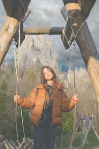 Portrait of a teenage girl on a wooden swing in the mountains.