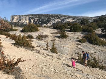 Family hiking on hill against sky on sunny day