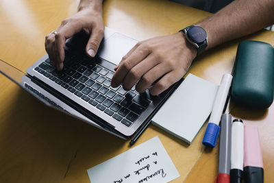 Cropped image of computer programmer typing on laptop at desk in startup company