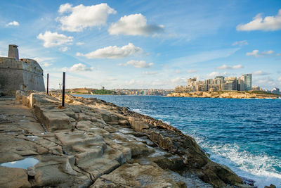 Scenic view of sea by buildings against sky