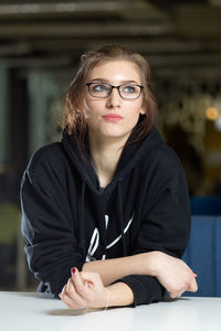 Thoughtful young woman leaning on table at home