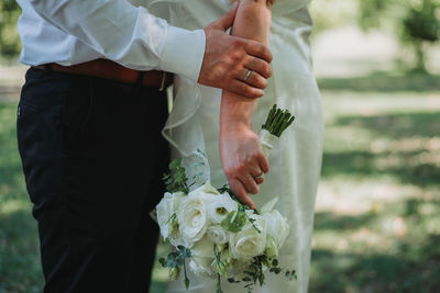 Midsection of bride holding bouquet