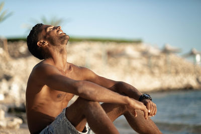 Side view of woman sitting on beach