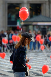 Side view of woman with red balloons