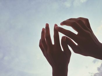 Low angle view of human hand against sky