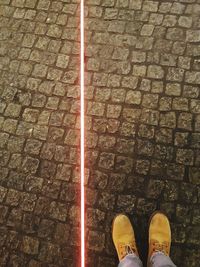 Low section of man standing on cobblestone street