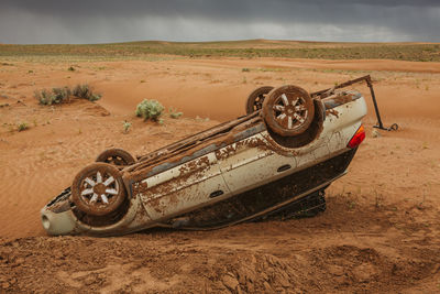 Old vintage car on sand at beach against sky