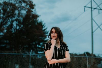 Young woman using mobile phone against sky