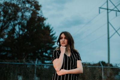 Young woman standing against sky