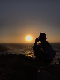 Silhouette man photographing at sunset