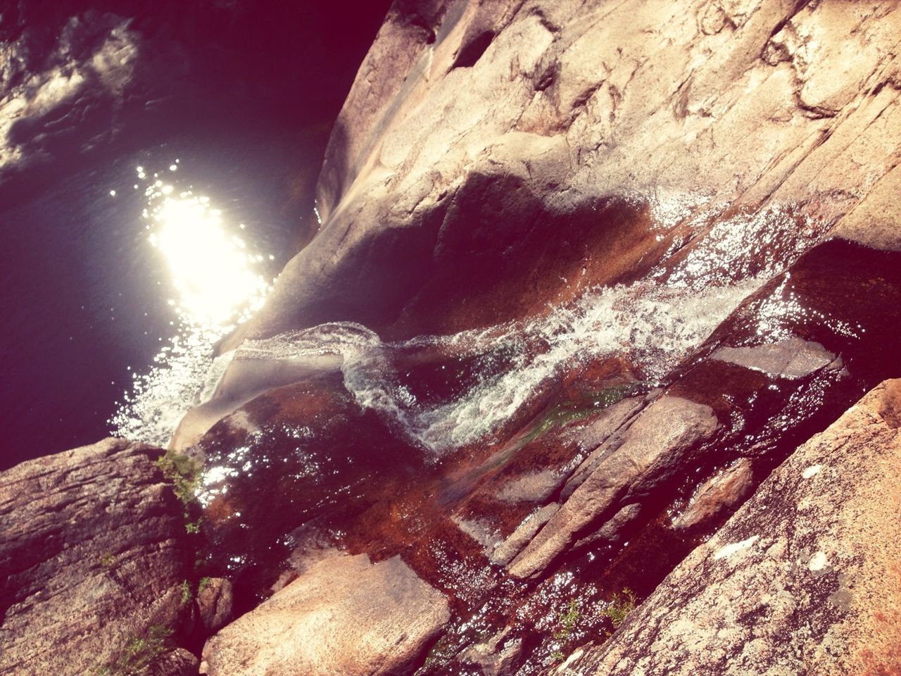 sunlight, rock - object, nature, rock formation, close-up, water, wood - material, outdoors, textured, no people, day, beauty in nature, motion, tranquility, rough, tree trunk, sunbeam, low angle view, rock, shadow