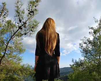 Rear view of woman standing by trees against sky / woman in the forest / forest view