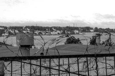 Metal fence by city against sky