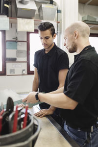 Teacher assisting male trainee over project in workshop