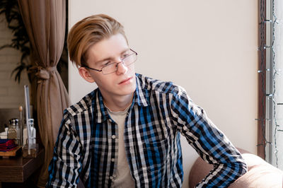 Young man looking away while sitting at home