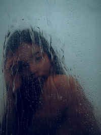 Portrait of woman in wet glass window