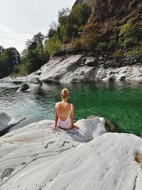 Woman sitting on rock against mountain