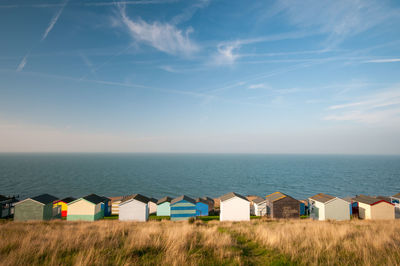 Beach huts by sea against blue sky