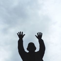 Silhouette man with arms outstretched against the sky