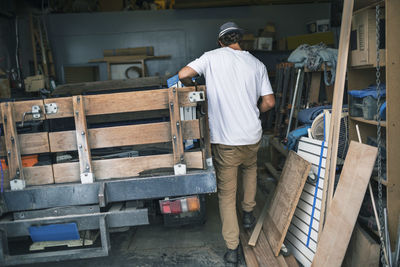 Rear view of carpenter walking by pick-up truck at workshop