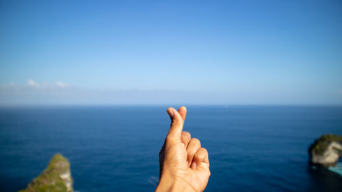 Cropped hand against sea