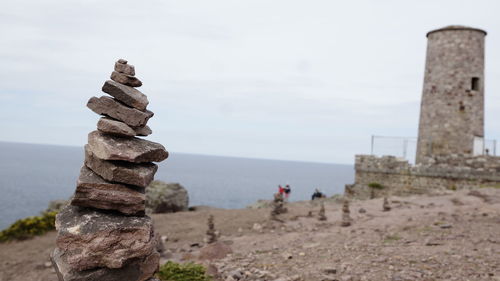 Stack of rocks by sea against sky