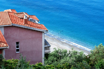 High angle view of houses by sea against blue sky