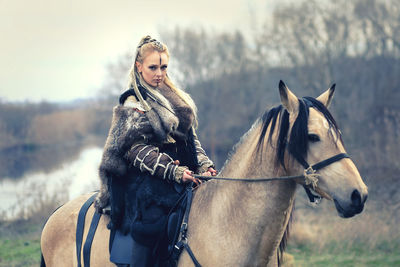 Portrait of woman riding horse in forest