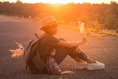Boy sitting on tree at sunset