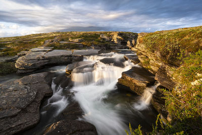 Scenic view of waterfall against sky