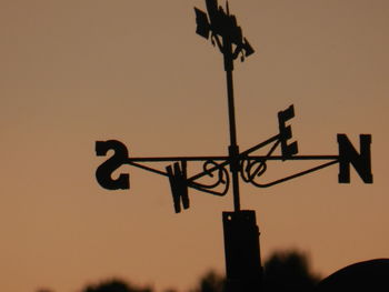 Low angle view of weather vane against sky