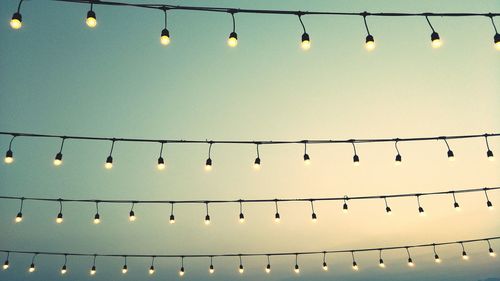 Low angle view of illuminated lights hanging against sky