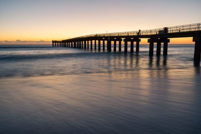 Bridge over sea against sky during sunset