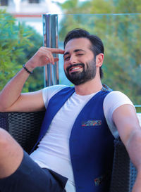 Portrait of young man holding camera outdoors