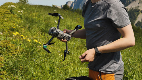 A man holds a quadcopter and prepares it for flight. launching a drone on a mountain hike