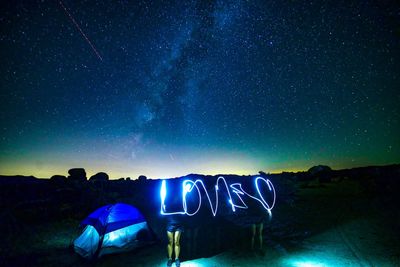 Light painting by tent against sky at night