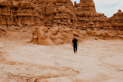 Man walking alone among hoodoo rocks in goblin valley