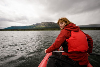 Portrait of man sitting on boat in river against sky