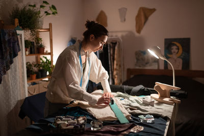 Female tailor measuring cloth in evening