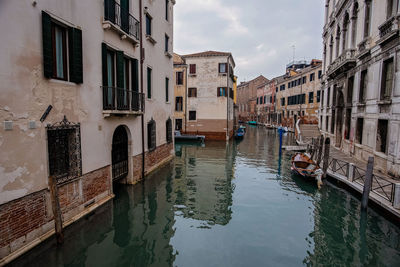 Canal amidst buildings in city against sky