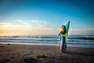 Boy standing on beach against sky during sunset